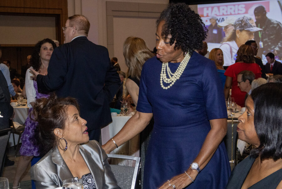 Two women wearing formal wear talk during a gala.